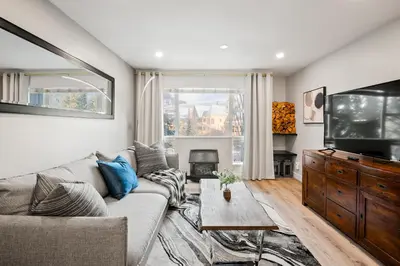 a living room with a couch and a tv at Ski In & Out, Heart of Upper Village in Whistler