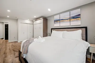 a bedroom with a large white bed with two paintings on the wall at Ski In & Out, Heart of Upper Village in Whistler