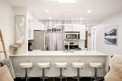 a kitchen with white cabinets and bar stools at Whistler Village, Private Hot Tub, Free Parking in Whistler