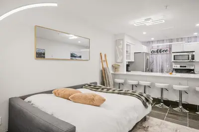 a white room with a bed and a kitchen at Whistler Village, Private Hot Tub, Free Parking in Whistler