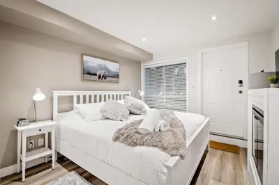 a white bedroom with a white bed and a window at Whistler Village, Private Hot Tub, Free Parking in Whistler