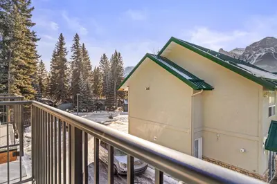 a building on a balcony with trees and mountains at B233 Mountain View 2BD 2BT AC BonFire BBQ Townhome Close to Banff in Canmore