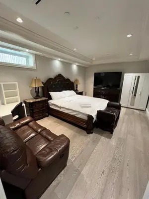 a large bedroom with a bed and a leather couch at Private Rooms in Vancouver West in Vancouver
