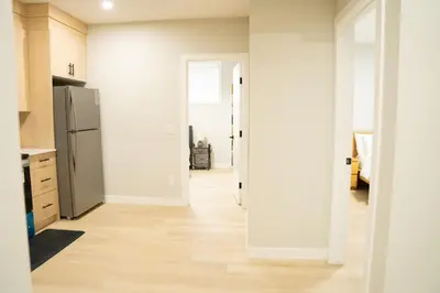 an open kitchen with a refrigerator and a hallway at The Old Trafford - Stylish 2 bed suite in Calgary