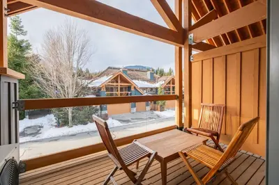 a table and two chairs on a porch with a large window at Montebello 4877 by Outpost Whistler in Whistler