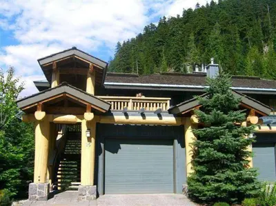 a house with two garage doors and a tree at Whistler Highcamp in Whistler