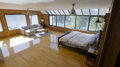 a bedroom with a bed and a living room with windows at Ozarks Luxurious Lakeside Villa at Harrison Lake in Harrison Hot Springs