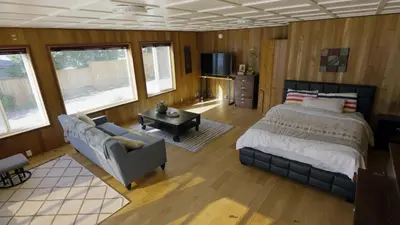 a bedroom with a bed and a couch and a tv at Ozarks Luxurious Lakeside Villa at Harrison Lake in Harrison Hot Springs
