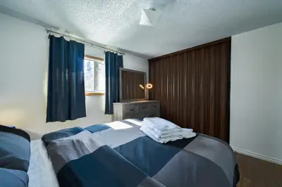 a bedroom with a bed with blue and white sheets at Cozy House in Haines Junction in Haines Junction