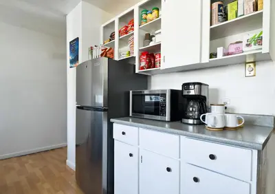 a kitchen with a stainless steel refrigerator and white cabinets at Cozy House in Haines Junction in Haines Junction
