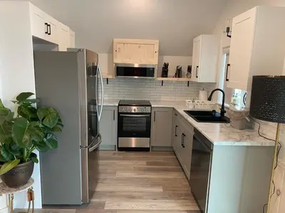 a kitchen with stainless steel appliances and white cabinets at Lakeside Cottage in Nanaimo
