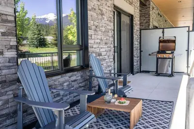 two chairs and a table on a patio with a grill at Rustic Retreat by Revelstoke Vacations in Revelstoke