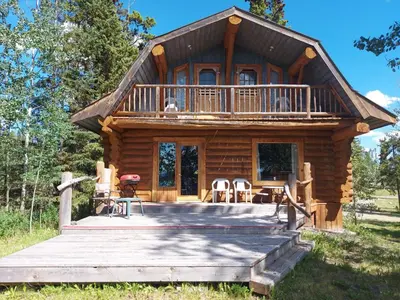 a log cabin with a porch and a deck at Escott Bay Resort in Anahim Lake