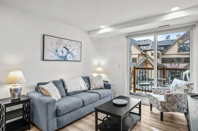 a living room with a couch and a large window at T202 BRAND NEW! The Mountain's Call- Mountain View Stay in Canmore