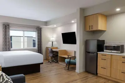 a hotel room with a bed and a kitchen with a desk at Baymont by Wyndham West Edmonton in Edmonton