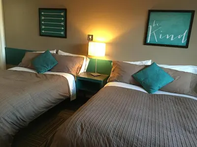 a room with two beds and a lamp on a wall at Canterbury Inn in Invermere