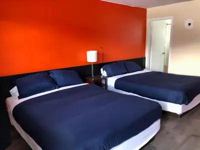 two beds in a room with a red wall at Canterbury Inn in Invermere