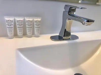 a sink with a faucet and three cups on a counter at Canterbury Inn in Invermere