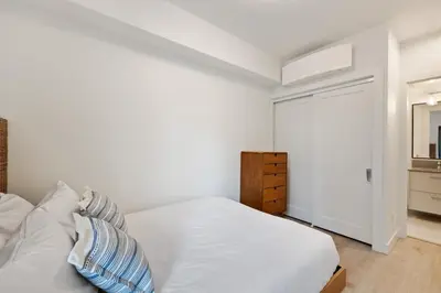 a white bedroom with a bed and a closet at Ocean View Townhouse #27 in Oyster Bay