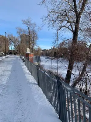 a snow covered sidewalk next to a fence with a sidewalk at Mission Historical Home in Calgary