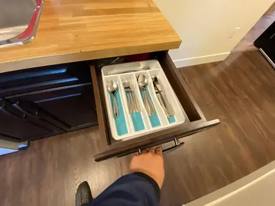 a person is reaching for a utensils in a drawer at New Dt Apartment Walk To All in Edmonton