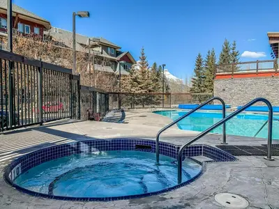 a hot tub in a patio next to a building at Freshly Remodeled - 2 King Beds- Breathtaking Views in Canmore