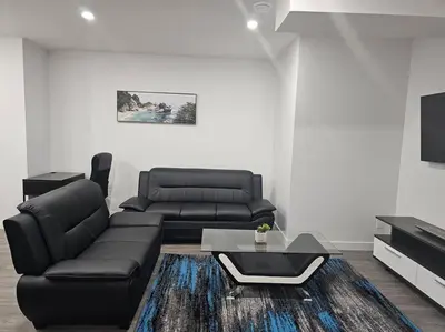 a living room with a black couch and a table at New 2 bdrm basement suite Seton in Calgary