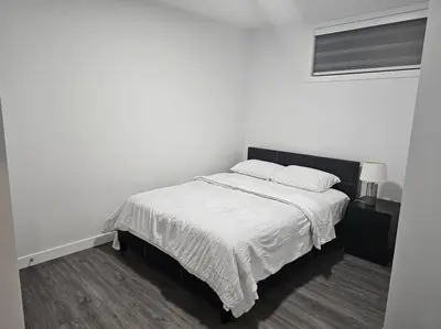 a white bedroom with a bed with two pillows at New 2 bdrm basement suite Seton in Calgary