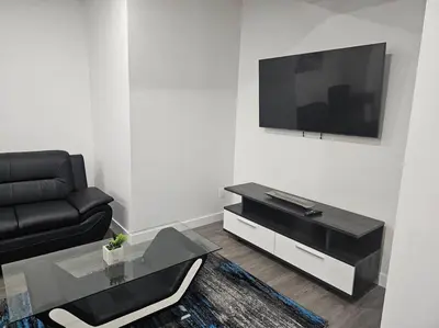 a living room with a black couch and a tv at New 2 bdrm basement suite Seton in Calgary