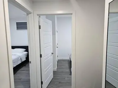 a bedroom with a door leading to a bedroom with a bed at New 2 bdrm basement suite Seton in Calgary