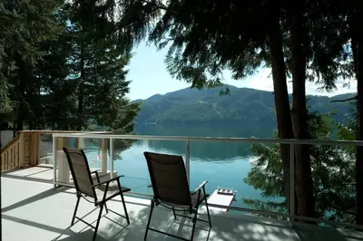 two chairs on a deck with a view of a lake at Private Ozarks Island Retreat in Agassiz