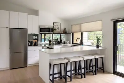 a kitchen with white cabinets and a large island with bar stools at Casa Bramble Luxury 2Bed Suite near UofA Hospital in Edmonton