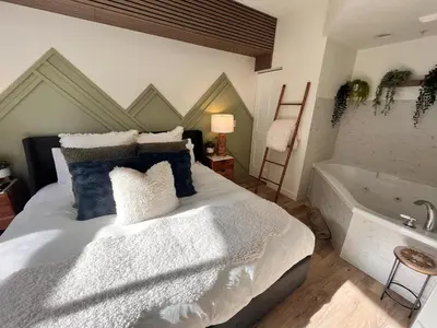 a bedroom with a large bed and a bath tub at Three Peaks Getaway Jacuzzi Suite - sleeps 4 in Canmore