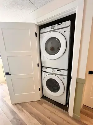 a washer and dryer in a room with a door at Three Peaks Getaway Jacuzzi Suite - sleeps 4 in Canmore