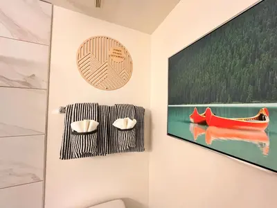 a bathroom with a tv and a red boat on the wall at Three Peaks Getaway Jacuzzi Suite - sleeps 4 in Canmore