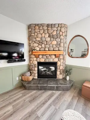 a living room with a stone fireplace and a tv at Three Peaks Getaway Jacuzzi Suite - sleeps 4 in Canmore