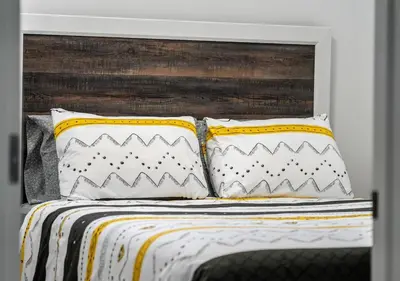 a bed with two pillows and a wooden headboard at Mountain Hideaway Two Bedrooms Free Park Pass in Cochrane