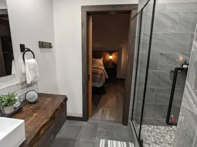 a bathroom with a shower and a bedroom with a bed at Skyline Suite 2Bdrm King in Valemount