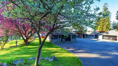 a tree in front of a building with pink flowers at Beaver Beach Vacation Home in Madeira Park