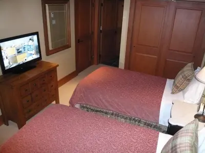 a bedroom with two beds and a flat screen tv at Whistler Ski In Ski Out in Whistler