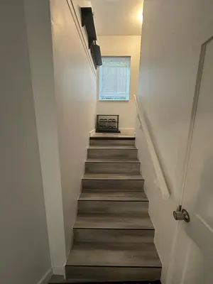 a stairway leading up to a room with a window at Serenity 1BR & 1 DEN Home at Folsom Ave in Coquitlam