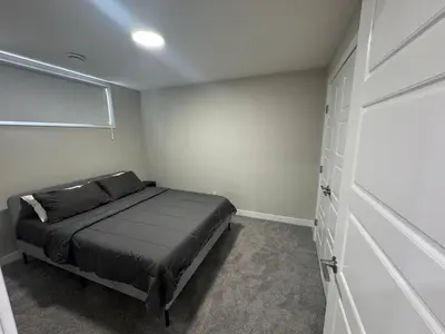 a small bedroom with a bed and a closet at Cozy 1 bedroom basement apartment in Airdrie