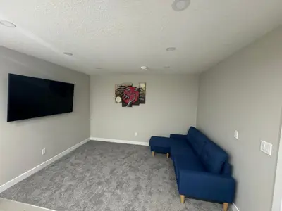 a living room with a blue couch and a flat screen tv at Cozy 1 bedroom basement apartment in Airdrie
