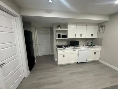 a kitchen with white cabinets and white appliances at Cozy 1 bedroom basement apartment in Airdrie