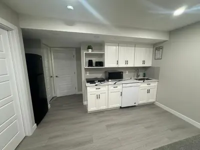a kitchen with white cabinets and a black refrigerator at Cozy 1 bedroom basement apartment in Airdrie