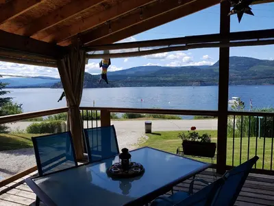 a screened in porch with a view of a lake at West facing Waterfront Cottage with private beach & buoy & dock access in Blind Bay