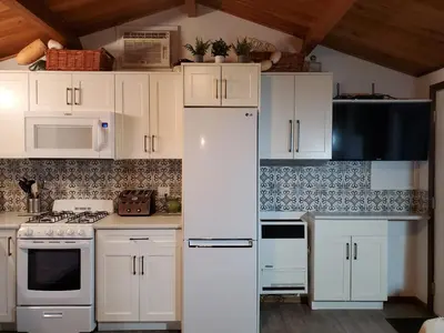a kitchen with white cabinets and white appliances at West facing Waterfront Cottage with private beach & buoy & dock access in Blind Bay