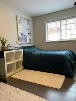 a bedroom with a bed with a black comforter and a window at Vancouver Airport 7 mins away Cozy room Richmond near YVR in Richmond