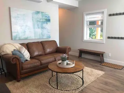 a living room with a brown couch and a table at Executive 1 Bedroom Lakeview Retreat in Shawnigan Lake
