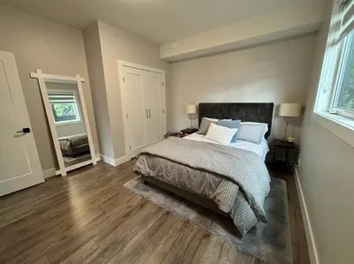 a bedroom with a large bed and a mirror at Executive 1 Bedroom Lakeview Retreat in Shawnigan Lake
